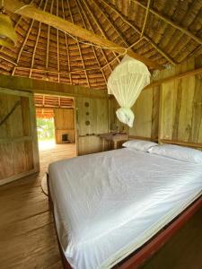 a bed in a room with a straw roof at Hostal Maguare-Reserva Indígena Maguare in Leticia