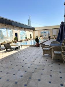 a patio with tables and chairs and a pool at Hotel Dera Bukhara in Bukhara
