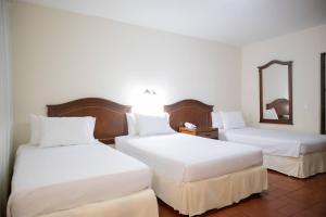 two beds in a hotel room with a mirror at Hotel Faranda Bolivar Cucuta, a member of Radisson Individuals in Cúcuta