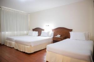 two beds in a hotel room with white sheets at Hotel Faranda Bolivar Cucuta, a member of Radisson Individuals in Cúcuta +145 photos