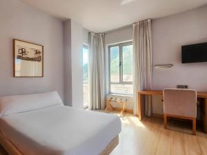 a bedroom with a bed and a desk and a window at Hotel Faranda Marsol Candas, Ascend Hotel Collection in Candás