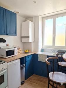 a kitchen with blue cabinets and a white microwave at La Plage in Fécamp