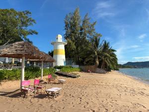 a lighthouse on a beach with chairs and a light house at Beach Front Condo Centerviews Bangsaray Floor 7 in Bang Sare