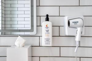 a bottle of soap and a soap dispenser on a bathroom wall at Comfort Suites Tijuana in Tijuana