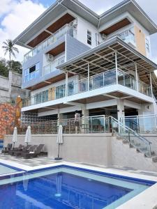 a building with a swimming pool in front of a house at Highlights Taal Lake View Resort in Santol