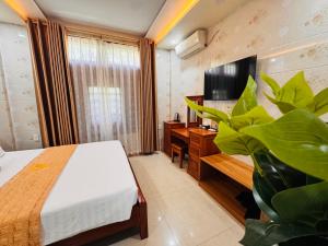 a bedroom with a bed and a desk and a plant at Thịnh Vượng Hotel in Dong Hoi