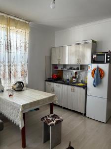 a kitchen with a table and a white refrigerator at Diamond Resort Cottage Issyk-Kul in Bosteri +3 photos