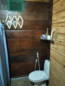 a bathroom with a toilet and a wooden wall at Silaa Cabana in Trincomalee