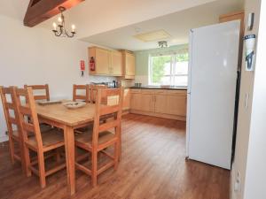 a kitchen with a wooden table and a white refrigerator at Whitbarrow 24 in Penrith