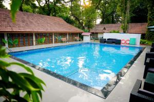 a large swimming pool with a house in the background at KTDC Kumarakom Gateway Resort in Alleppey