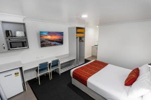 a bedroom with a bed and two chairs in it at Econo Lodge Alabaster Motel Cowra in Cowra