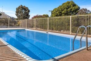 a swimming pool with a fence around it at Econo Lodge Alabaster Motel Cowra in Cowra