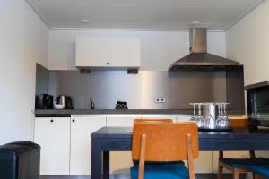 a kitchen with white cabinets and a blue table with chairs at 't Achterhuis (8 persons) in Otterlo
