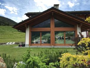 a house with large glass windows in a field at Chalet Taulei tra Bormio e Livigno in Valdidentro