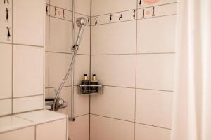 a shower in a bathroom with white tiles at Eiger Guest House - Grindelwald in Grindelwald +36 photos