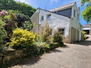 a white house with a stone wall and flowers at Primrose Cottage peaceful room and private garden in Helston