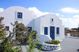 a white house with a blue door and some flowers at Pergeri Apartments in Imerovigli