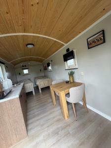 a living room with a wooden ceiling and a table and chairs at Shepherd Hutten Hunsel in Hunsel +15 photos