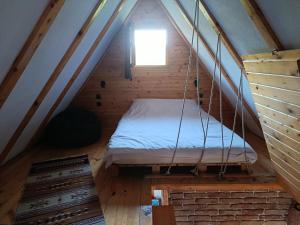 a bed in the attic of a wooden house at Koliba La Perla in Banja Luka