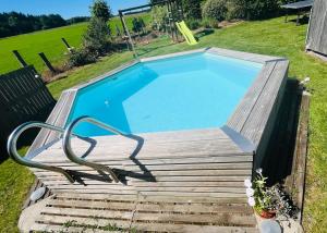a swimming pool with a wooden deck and a swimming pool at Le cocoon de Nanou in Anloy