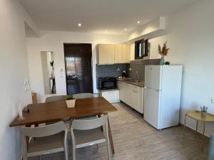 a kitchen with a table and a white refrigerator at Golden Evelyn in Agia Paraskevi