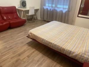 ein Schlafzimmer mit einem Bett und einem roten Sofa in der Unterkunft Affittacamere D&B in Pogliano Milanese