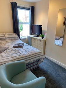 a bedroom with a bed and a chair and a tv at Bide a Sea in Gorleston-on-Sea