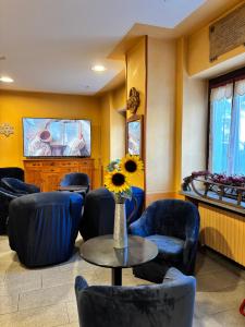 Ein Wartezimmer mit Stühlen, einem Tisch und einer Vase mit einer Sonnenblume. in der Unterkunft Hotel Sommeiller in Bardonecchia