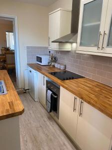 a kitchen with white cabinets and a stove top oven at Bide a Sea in Gorleston-on-Sea