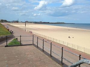 a beach with a fence and people on the beach at Bide a Sea in Gorleston-on-Sea