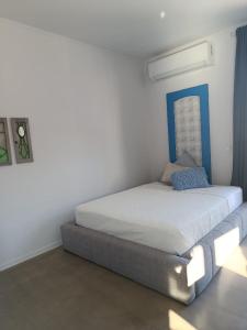 ein Bett in einem weißen Zimmer mit blauem Kopfteil in der Unterkunft Hellas4ever in Chrysoupolis