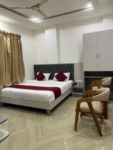 a bedroom with a bed with red pillows and a chair at Hotel Anand Inn in Kota