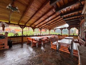 a restaurant with wooden tables and benches in a pavilion at Pensiunea Codrea - Wagner in Lazu Baciului