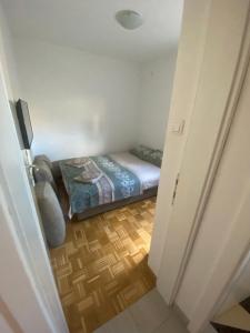 a small bedroom with a bed and a wooden floor at APARTMAN SEVEN free parking in Gornja Toplica
