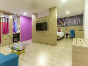 a living room with a tv and a couch and a table at Ibis Styles Bangkok Sukhumvit 50 in Bangkok