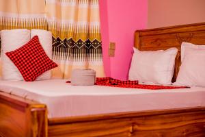 a bed with red and white pillows on it at Olivia Green Lodge in Arusha