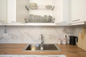 a kitchen counter with a sink and white cabinets at Oasis White Terra in Durrës +20 photos