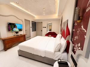 a bedroom with a large white bed and a television at Hotel Nova Bloom in Ahmedabad