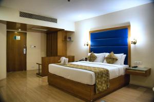 a bedroom with a large bed with a blue headboard at Peerless Hotel Hyderabad in Hyderabad