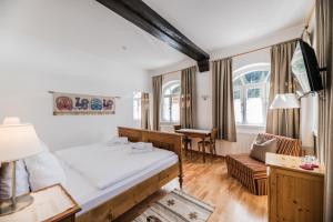 a bedroom with a bed and a desk and a chair at Hotel Dolomitenhof & Chalet Alte Post in Sesto