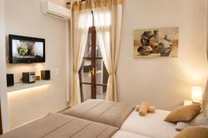 a bedroom with a bed and a tv and a window at Enetiko Rooms in Chania
