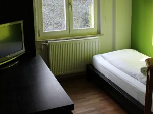 Habitación pequeña con cama y TV. en Pension Glücklich, en Horgenzell
