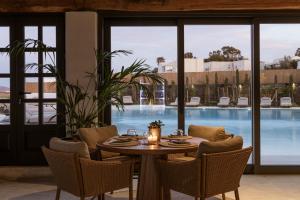 a dining room with a table and chairs and a pool at NĒRO Boutique Hotel in Imerovigli