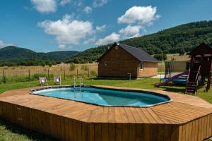 a pool with a wooden deck and a playground at Wilcza Polana Domki koło Międzygórza z jacuzzi i sauną in Jaworek