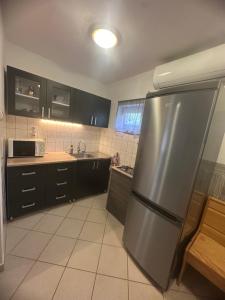 a kitchen with a stainless steel refrigerator and black cabinets at Gréta Apartman in Ábrahámhegy