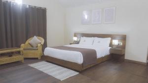 ein Schlafzimmer mit einem großen Bett und einem Stuhl in der Unterkunft Colonial 44 in Kohīma + 12 Fotos