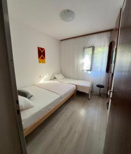 a small bedroom with two beds and a window at Guest House Oleander in Petrovac na Moru
