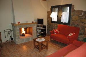 sala de estar con chimenea y sofá rojo en Cal Miger, en Gualter