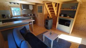 a living room with a blue couch and a kitchen at Domek Pod Sosnami in Kuźnica Nowa