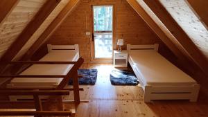 a attic room with two beds and a window at Domek Pod Sosnami in Kuźnica Nowa